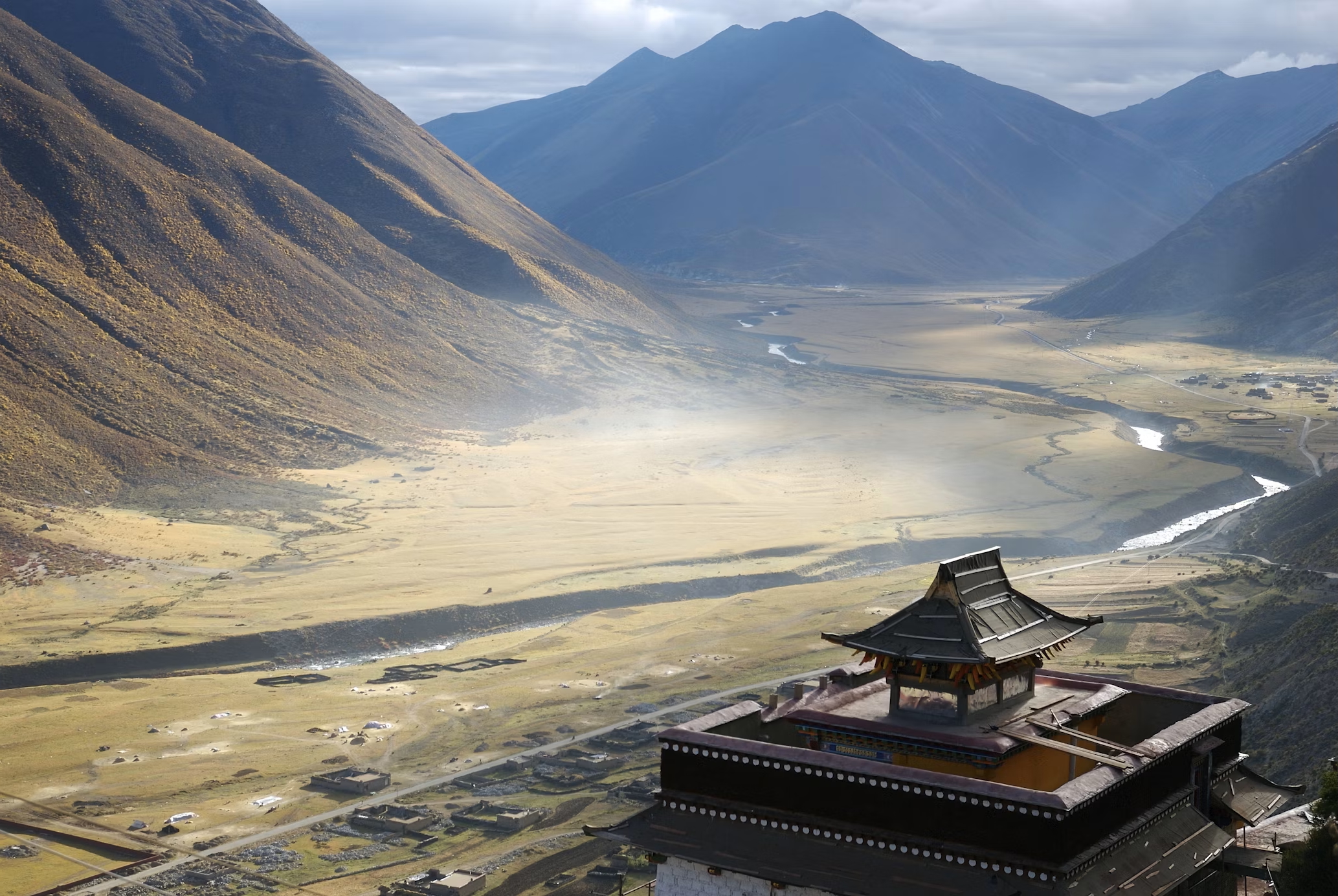 A monastery above a wide valley, mountains beyond