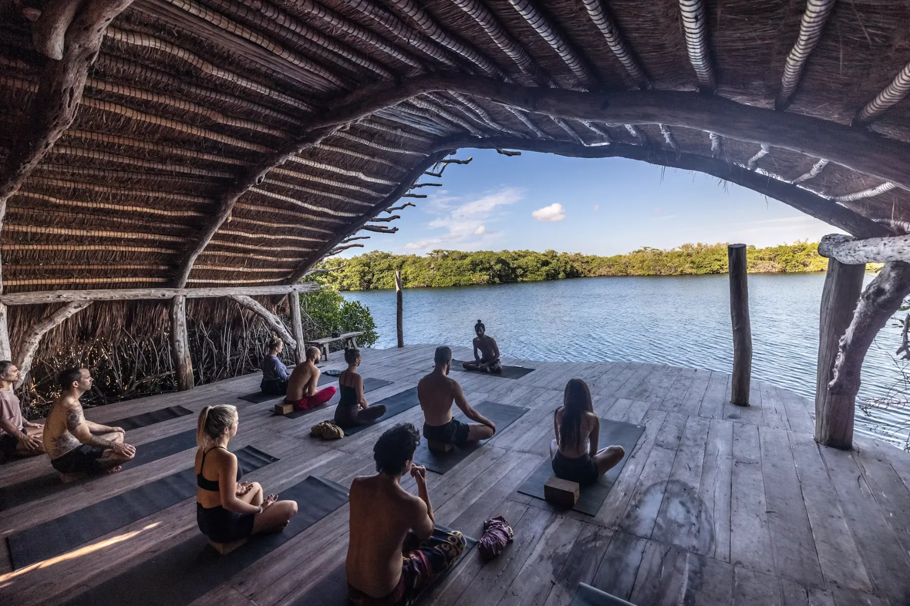 A group meditating on a deck over the water